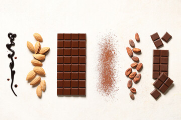 Sweet chocolate with almond nuts, cocoa beans and powder on white background