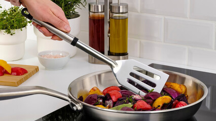 Closeup of a person steering veggeis in a frying pan. © Carterson