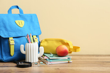 Set of stationery, school backpack and apple on wooden table