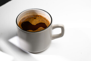 White cup of coffee in soft light isolated on a white background. Top view