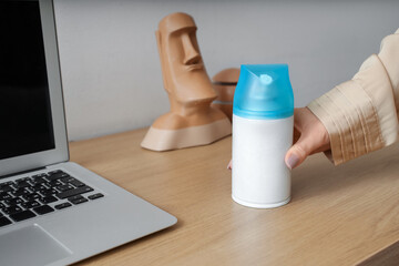 Woman with air freshener on table at home, closeup