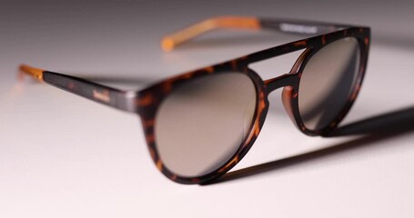 Unisex sunglasses on white background appearing from the dark. Movement of the shadow. Play of light. 