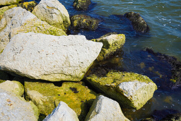 Ocean waves, crashing onto large rocks.