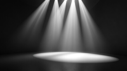   Black & white photo of 3 spotlights illuminating a dark room, casting a spotlight on the floor