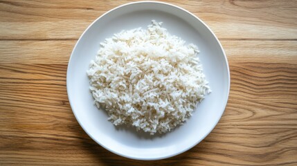 Cooked Thai Jasmine rice on a white plate, placed on a wooden surface, viewed from above. Authentic Thai meal presentation.