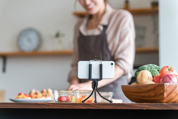 キッチンでスマホのアプリを見ながら理料理をする主婦
