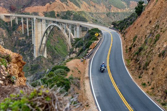 Motorcycle rides curvy road across Bixby Bridge California coast highway 1