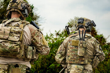Fototapeta premium A group of military men in combat gear patrol in the middle of a desert and tropical jungle. Soldiers in full combat gear in dry weather conditions assemble and march on a mission.