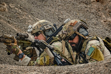 A group of military men in combat gear patrol in the middle of a desert and tropical jungle....