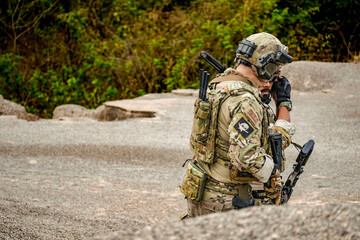 A group of military men in combat gear patrol in the middle of a desert and tropical jungle. Soldiers in full combat gear in dry weather conditions assemble and march on a mission.