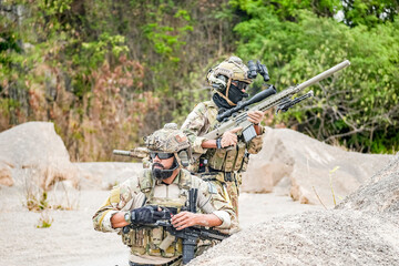 A group of military men in combat gear patrol in the middle of a desert and tropical jungle....