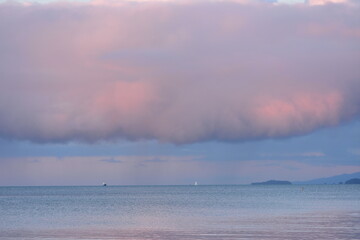 Scattered rain pouring from pink clouds into inner Hauraki Gulf. Location: Takapuna Auckland New Zealand