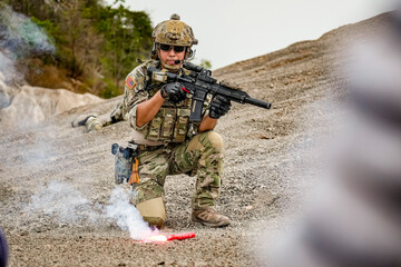 A group of military men in combat gear patrol in the middle of a desert and tropical jungle....
