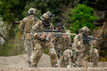 A group of military men in combat gear patrol in the middle of a desert and tropical jungle....