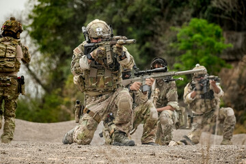 A group of military men in combat gear patrol in the middle of a desert and tropical jungle....
