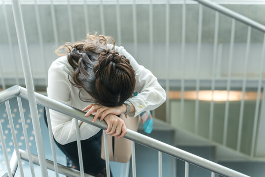階段で体調不良になりうずくまるビジネスウーマン（貧血・立ちくらみ・目眩）
