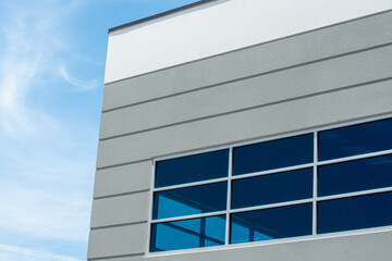 Obraz premium The exterior wall of a contemporary commercial style building with aluminum metal composite panels and glass windows. The futuristic building has engineered diagonal cladding steel frame panels.