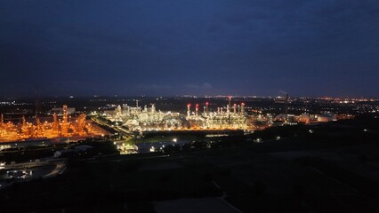 High angle view of industrial plant with pipes and tanks for mixing chemicals and gases at night.