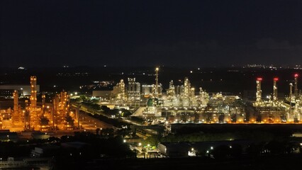 High angle view of industrial plant with pipes and tanks for mixing chemicals and gases at night.