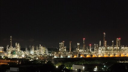 High angle view of industrial plant with pipes and tanks for mixing chemicals and gases at night.