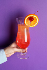 Woman with glass of refreshing cocktail on purple background, closeup