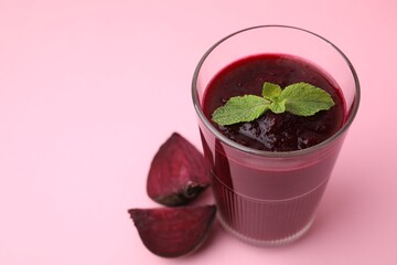 Fresh beetroot smoothie in glass and beet on pink table, closeup. Space for text