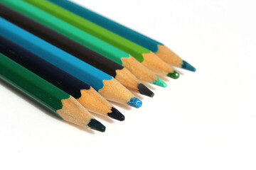 Row of green and blue sharpened colored pencils on a white background