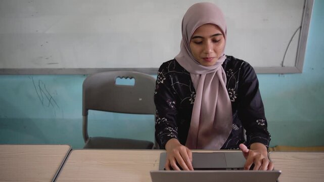 Asian Muslim business woman in hijab headscarf working with computer laptop in the classrom. Business people, education, diversity and office concept.