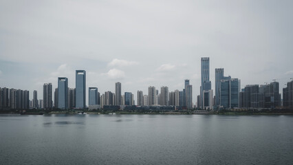 Fototapeta premium Captivating Urban Skyline Reflected in Calm Water Under a Cloudy Sky