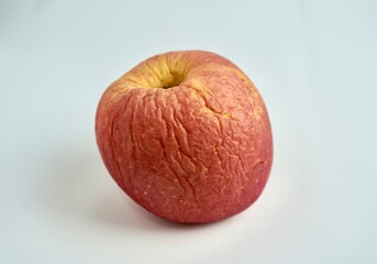 One dry and wrinkled rotten fuji apple fruit. Object photography isolated on horizontal white background.