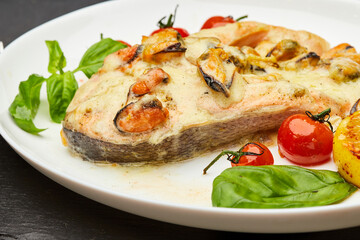 Delicious baked salmon steak with cream sauce and mussels is served on a plate and ready to eat