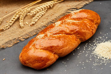 Freshly baked braided bread with sesame seeds on rustic background, ideal for bakery food projects