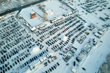 Aerial view of vehicle open market lot with many cars for sale parked and people customers walking in winter