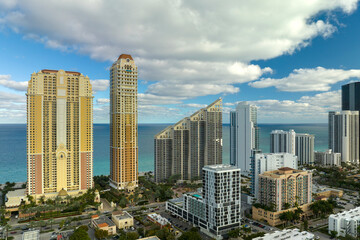 Fototapeta premium High angle view of Sunny Isles Beach city with expensive highrise hotels and condo buildings on Atlantic ocean shore. American tourism infrastructure in coastal southern Florida