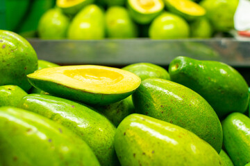 Display of avocados with one avocado split in half on top of the others at a farmer's market in Medellin, Colombia.