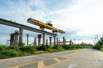 Large yellow launching gantry crane on top of elevated concrete pillars, used in bridge or railway...