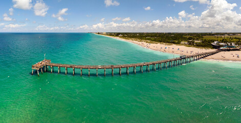 Summer landscape at Venice fishing pier in Florida. Ocean surf waves crashing on warm sandy beach