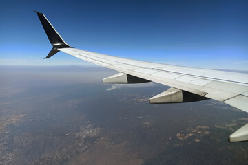Fototapeta premium View through airplane window of commercial jet plane wing flying high in the sky. Air travelling concept