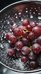 High-Angle Shot of Freshly Washed Grapes in a Colander with Water Droplets Glistening on the Surface, Captured Using Cool, Diffused Lighting from Above to Highlight the Freshness
