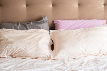 Cozy bed with colorful pillows and beige headboard. Neat and inviting bedroom set.