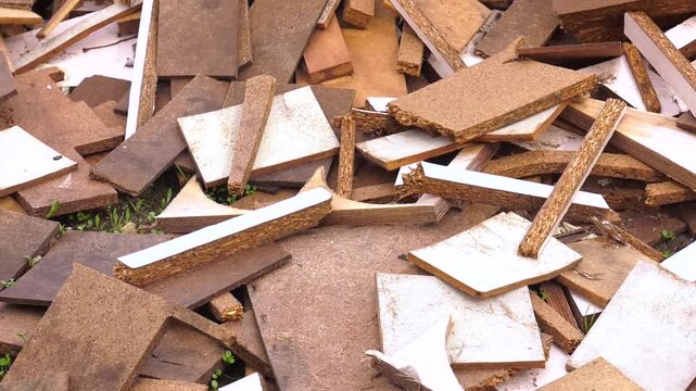 Chipboard trimmings. Industrial waste of furniture production. Waste production. Large pile of furniture production waste. Various pieces of wood, chipboard and mdf piled in a heap in the workshop
