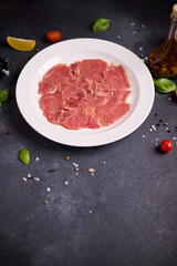 tuna carpaccio - slices of fresh raw tuna fillet on white ceramic plate