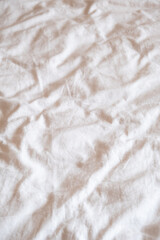 Wrinkled neutral fabric texture with soft lighting on plain background.