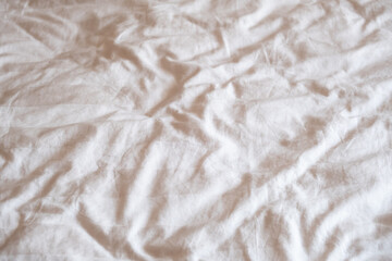 Wrinkled neutral fabric texture with soft lighting on plain background.