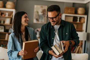 Embraced couple holding a books in their apartment living room