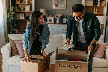 Young couple packing things in boxes. packing, donations, moving, new beginning concept