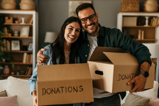 Happy couple moving into a new house. Cheerful couple carrying cardboard boxes and entering in their new apartment. Donations and moving in concept
