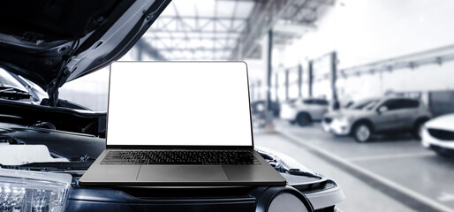 Grey laptop with blank white screen on the car engine compartment in the auto repair service garage , banner with copy space for text , Car repair and maintenance concept