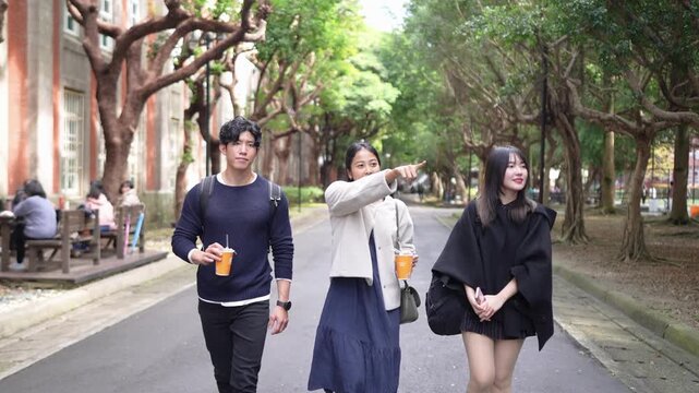 In Taipei's Da'an District, a slow-motion video captures a young Taiwanese man and woman with a South Asian woman, all in their twenties, walking and chatting amicably on a university campus.