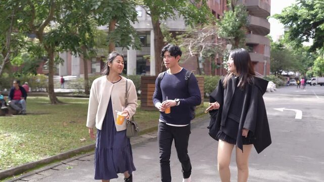 In Taipei's Da'an District, a slow-motion video captures a young Taiwanese man and woman with a South Asian woman, all in their twenties, walking and chatting amicably on a university campus.